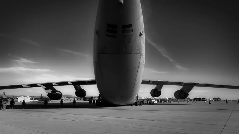 Black-and-white view of a large cargo aircraft parked on an airfield flight line