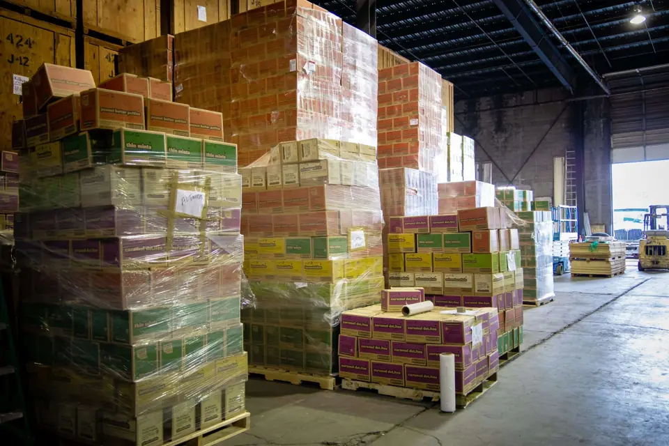 Shrink-wrapped pallets stacked high along a wide aisle in the O'Brien's warehouse